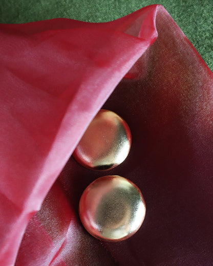 Two gold buttons on a red fabric background