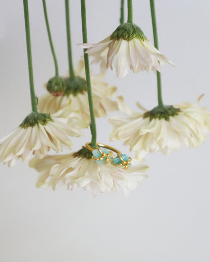 Gold ring with raw emerald stones, handmade in Colombia. Styled on soft white chrysanthemums. 