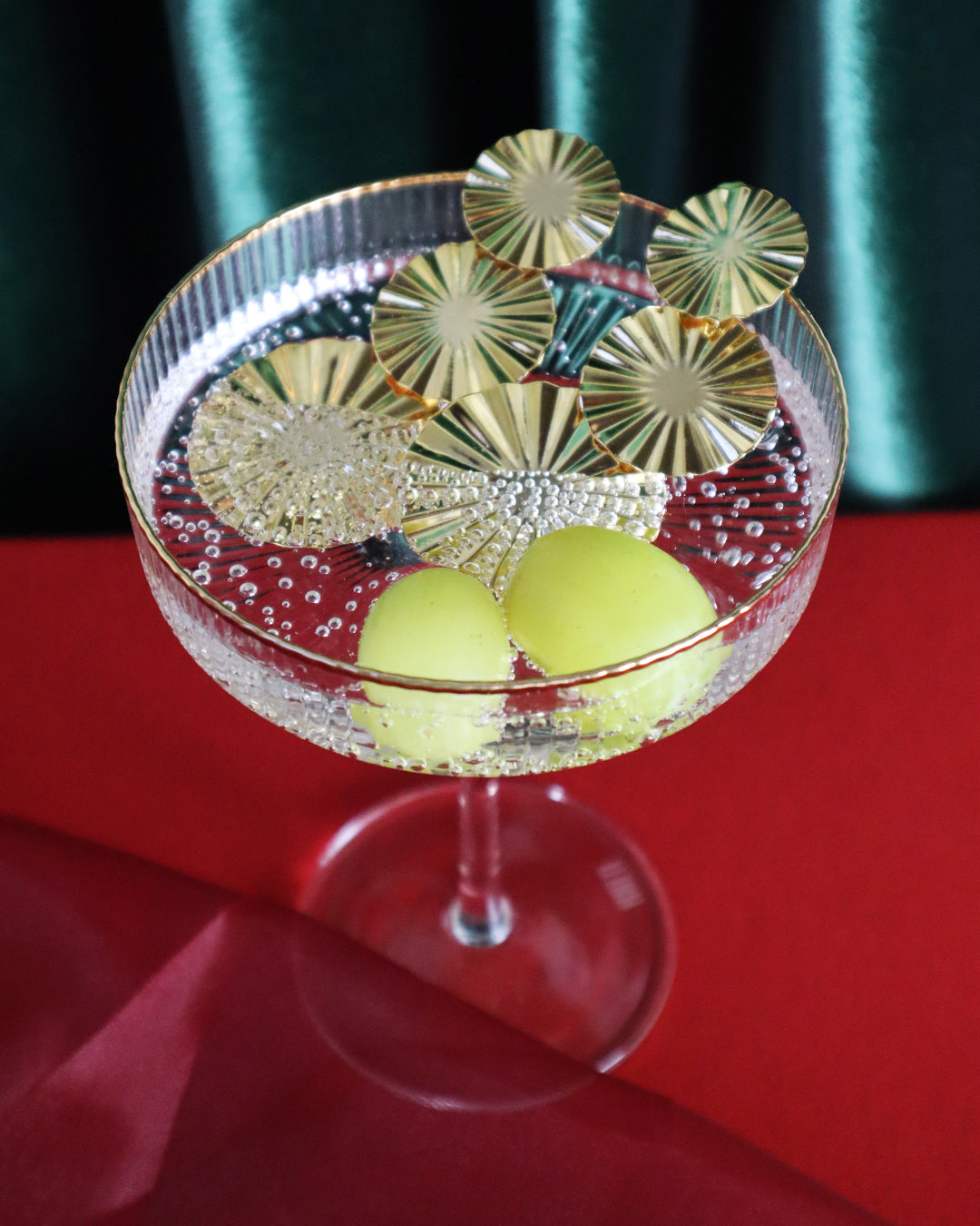 Decorative glass with 2 grapes and Dani earrings on a red table cloth